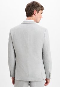 Hellgrauer Blazer aus strukturiertem Stoff, mit Schlitze hinten und knöpfbaren Manschetten. Taillierte Passform mit einem glatten, modernen Design.