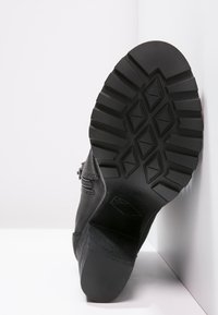 Sole nera di stivale con un design testurizzato che presenta motivi a diamante e rettangolo, realizzata in gomma con una presa robusta.