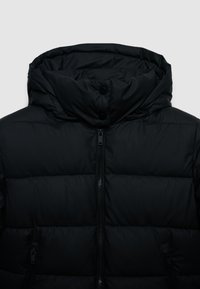 Giacca invernale nera imbottita con alto colletto, due bottoni a pressione sul colletto, chiusura frontale con zip e tasche con zip su ciascun lato.