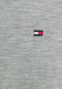 Grijze stoffen t-shirt met een klein geborduurd logo met rode, witte en blauwe secties. Soepele textuur met een klassiek ronde hals ontwerp.