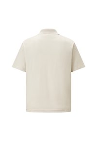 Polo crème à manches courtes avec un col classique, fabriqué en tissu lisse, présentant une coupe droite sans motifs ni accents visibles.