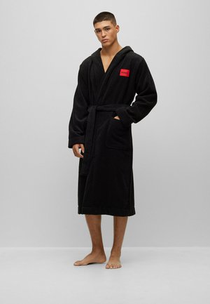 Black hooded bathrobe in soft fabric, featuring a front pocket and a red logo patch. The robe has a tie belt and knee-length design.
