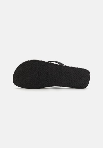 Sort flip-flop sål med struktureret gummi og gentagende logo-mønster. Åben tå-design og flad profil til afslappet brug.