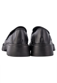 Paire de mocassins en cuir noir avec semelles épaisses texturées vues de dos sur fond blanc.