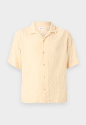 Πουκάμισο με κοντά μανίκια, ανοιχτό μπεζ, με γιακά spread και πέντε ορατά κουμπιά σε μονόχρωμο φόντο.