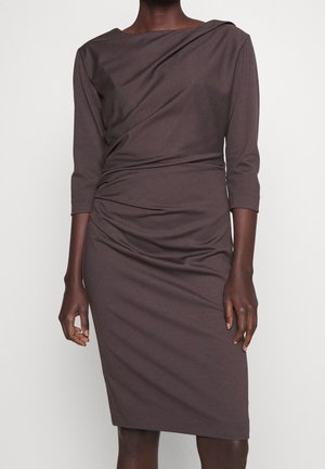 Robe marron foncé jusqu'aux genoux avec manches trois-quarts et un subtil drapé à l'avant, portée par une personne debout.