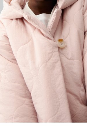 Różowa pikowana kurtka z kapturem, zapinana na jeden guzik, wykonana z miękkiej, teksturowanej tkaniny. Charakterystyczny wzór to zaokrąglone, pikowane kształty.