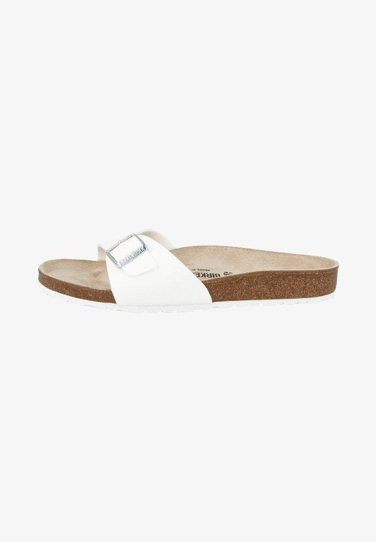 Vita sandal med bred rem, silverfärgad spänne, strukturerad korkinlägg och vit gummisula. Enkel design, lätt konstruktion.