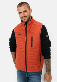 Orangen gesteppte Weste mit hohem Kragen, Reißverschlusstaschen und schwarzem Rippstrickärmel; verfügt über ein dezentes Logo und einen strukturierten Stoff.