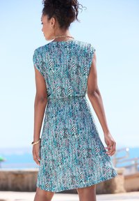 Īsām piedurknēm kleita ar krāsainu zigzag rakstu tirkīza, rozā un melnā krāsā. Satur elastīgu jostasvietu un brīvu siluetu.