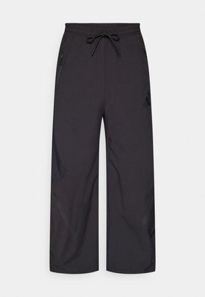 Sorte treningsbukser med løs passform, snor i midjen og glidelåslommer. Laget av glatt, lett stoff med subtil matt overflate.