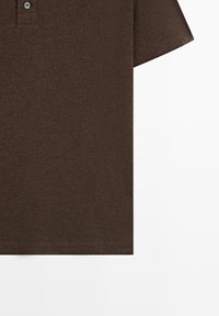 Brązowa koszulka polo wykonana z fakturowanej tkaniny, z plisą na trzy guziki i krótkimi rękawami. Prosty, dopasowany krój o czystych liniach.