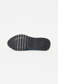 Fekete gumi sneaker talp, textúrált mintázattal és tapadásgörbékkel. Kerek orr és kék textil felső széle van.