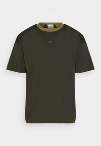 Camiseta de manga corta verde oscuro con cuello redondo y un collar de color verde oliva claro en contraste; presenta un pequeño logo negro en el pecho.