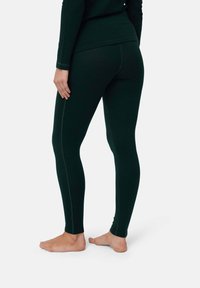 Mörkgröna, figurnära leggings gjorda av ett strukturerat tyg, med kontrasterande sid sömmar och hög midja, designade för komfort.