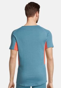 Maglietta sportiva a maniche corte con un corpo blu e pannelli laterali in rete arancione, realizzata in materiale traspirante e dotata di scollo rotondo.