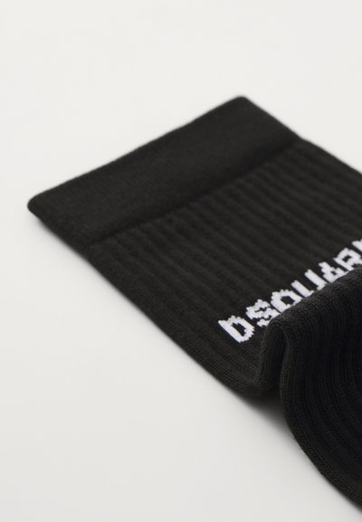 Melnas ribotas zeķes ar balto "DSQUARED2" logotipu, kas izstrādāts augšpusē. Tām ir ērts, elastīgs maliņa, kas nodrošina drošu piegulšanu.