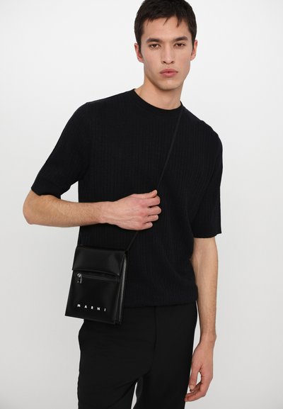 Bolso de hombro de piel negra con cerradura de solapa, bolsillo con cremallera y logotipo "MARNI" grabado en blanco. Diseño texturizado con forma delgada.
