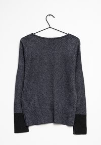 Maglione a maniche lunghe grigio scuro in maglia con polsini neri appeso a un gancio di filo nero su uno sfondo bianco.