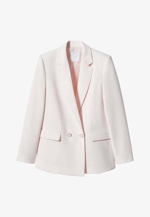 Donna con capelli castani lisci indossa un blazer rosa chiaro e pantaloni abbinati, in piedi con le spalle rivolte verso la fotocamera su uno sfondo semplice.