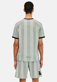 Ljusgrön sporttröja och shorts-set, med ett geometriskt mönster, svarta detaljer på kragen och ärmarna, tillverkad av ventilerande tyg.