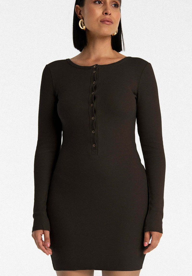 Długosłone, ciemnobrązowa sukienka z prążkowanego materiału, z okrągłym dekoltem i rzędem sześciu dekoracyjnych guzików z przodu. Gładka tekstura.