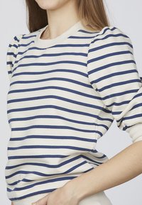Stribet pullover sweater i creme med marineblå vandrette striber, med rund halsudskæring og puffede ærmer. Glat bomuldsstof.