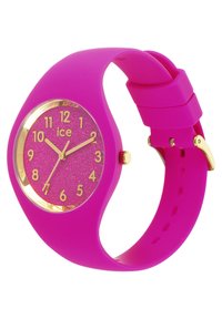 Montre en silicone rose avec un cadran rond pailleté rose, des index horaires dorés et un accent doré autour du verre. Bracelet lisse avec fermeture à boucle.