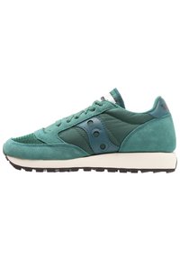 Sneaker en suède vert et textile avec des accents en maille, bout arrondi, logo teal contrastant et semelle en caoutchouc. Système de laçage.
