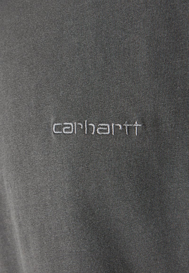 Grå bomullströja med ribbat mönster, med en vit broderad "carhartt"-logotyp på framsidan. Enkelt design, avslappnad stil.