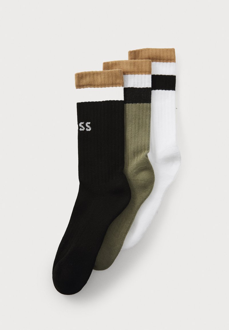 Trois paires de chaussettes côtelées en noir, vert olive et blanc, avec des bords rayés contrastants en marron et noir. Le texte sur la chaussette noire indique "SS."