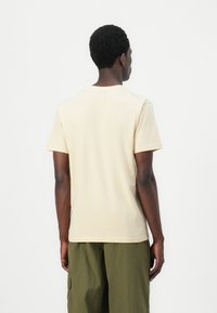 Beige short-sleeve t-shirt made of soft fabric, with a crew neckline and straight cut. The back shows a simple, seamless design.