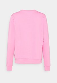 Sweatshirt rose à manches longues, col rond et détail d'ourlet fendu. Le tissu semble doux et confortable, avec une texture lisse et uniforme.