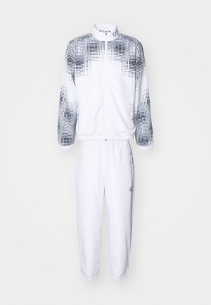 Completo sportivo bianco composto da un giubbotto con zip e un motivo a pois neri sulle maniche, abbinato a pantaloni affusolati con polsini elastici.