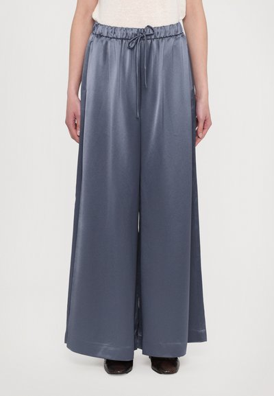 Pantaloni largi dintr-un material moale, lucios, de culoare gri închis. Aceștia au o talie elastică cu șnur și două buzunare laterale.
