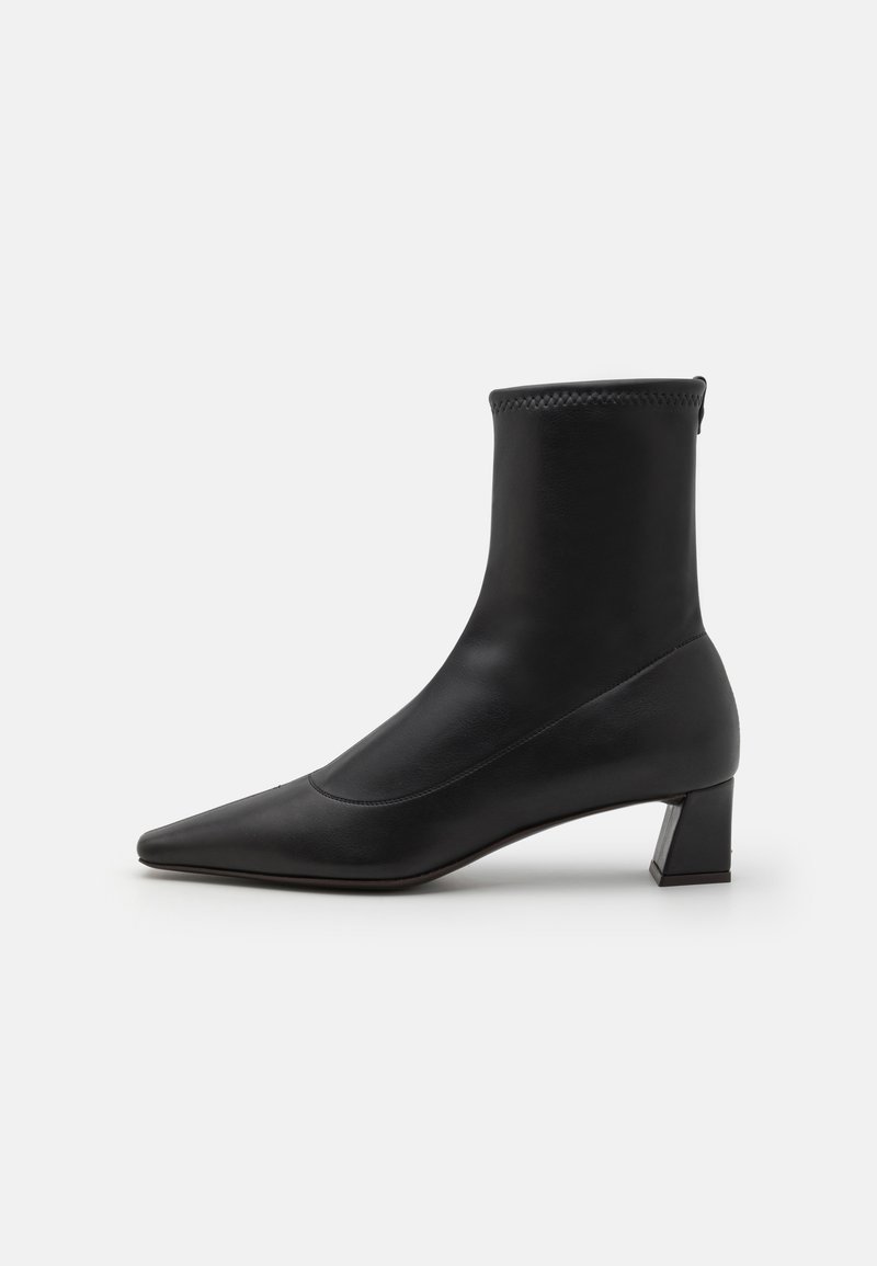 Botine negre din piele netedă, cu vârf ascuțit și toc pătrat. Partea superioară are un margine texturată pentru un detaliu suplimentar.