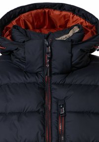 Czarna kurtka puchowa z wysokim kołnierzem, kontrastową pomarańczową podszewką i centralnym zamkiem błyskawicznym z czarno-czerwonymi akcentami. Miękkie futrzane wykończenie.
