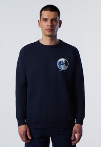 Felpa blu navy in materiale morbido, con scollo rotondo, polsini a coste e un logo a onde circolari sul lato sinistro del petto.