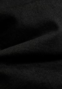 Närbild av slät svart tyg med synlig vävstruktur och mjuka veck som skapar milda skuggor och höjdpunkter.