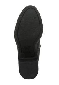 Black shoe sole featuring a textured surface, oval shape, and a distinct "V" logo. The design includes curved lines and a smooth heel.