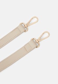 Páska z béžové umělé kůže s kovovými zlatými sponami. Plochý design, hladká textura a oboustranné zapínání pro připevnění.