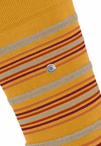 Gestreifte Socken mit einem lebhaften gelben Grundton und horizontalen roten und beigen Streifen, akzentuiert durch einen silbernen Logo-Button.