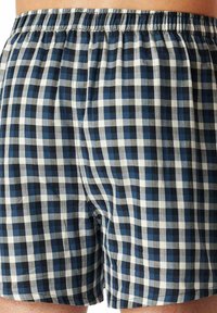 Boxer blu e bianchi a scacchi realizzati in tessuto leggero. Presentano una vita elastica e una vestibilità ampia per il massimo comfort.