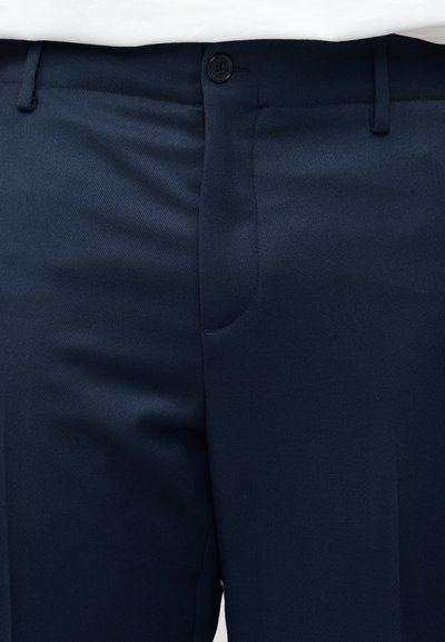 Σκούρο μπλε παντελόνι ναυτικού τύπου με κουμπί και φερμουάρ, θηλιές για ζώνη και ορατή μέση πάνω σε λευκό φόντο.