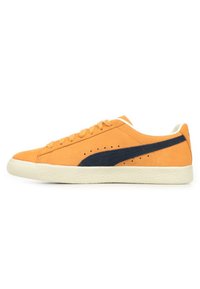 Sneaker in suede arancione con accenti blu navy, punta rotonda, lacci sulla parte anteriore, perforazioni sottili e suola in gomma cremoso testurizzata.