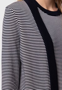 Randig långärmad topp i marinblått och vitt. Har en solid marinblå texturerad panel framtill. Mjuk, stickad tyg, rund halsringning.