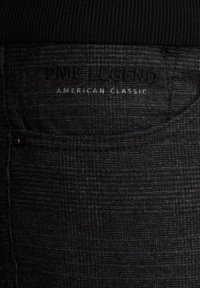 Zwarte broek van een textuurstof met subtiele patronen. De tailleband is effen, met de bedrukte merknaam "PME LEGEND AMERICAN CLASSIC."