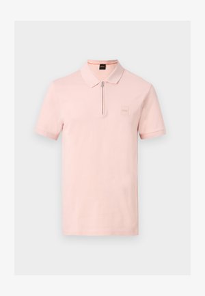 Ανοιχτό ροζ πόλο με κοντά μανίκια, φερμουάρ στη γιακά και διακριτικό λογότυπο της μάρκας στο αριστερό στήθος πάνω σε μονόχρωμο φόντο.