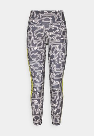 Leggings en tissu extensible gris foncé avec un motif abstrait blanc et des bandes latérales vert vif. Taille haute, coupe ajustée.