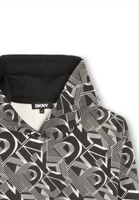 Sweat à capuche avec un motif géométrique en noir et blanc, fabriqué en tissu doux. L'étiquette affiche "DKNY" avec une taille 8.